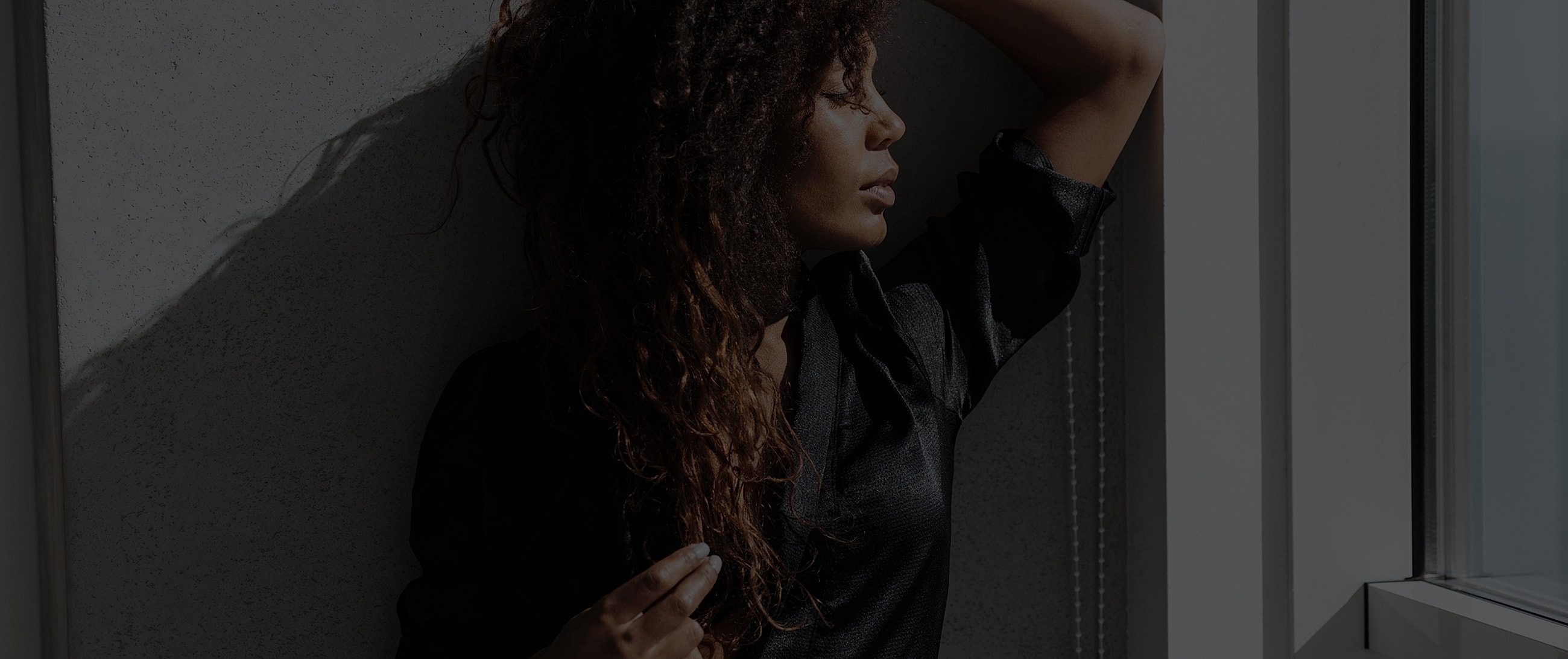 Woman with curly hair leaning against a wall