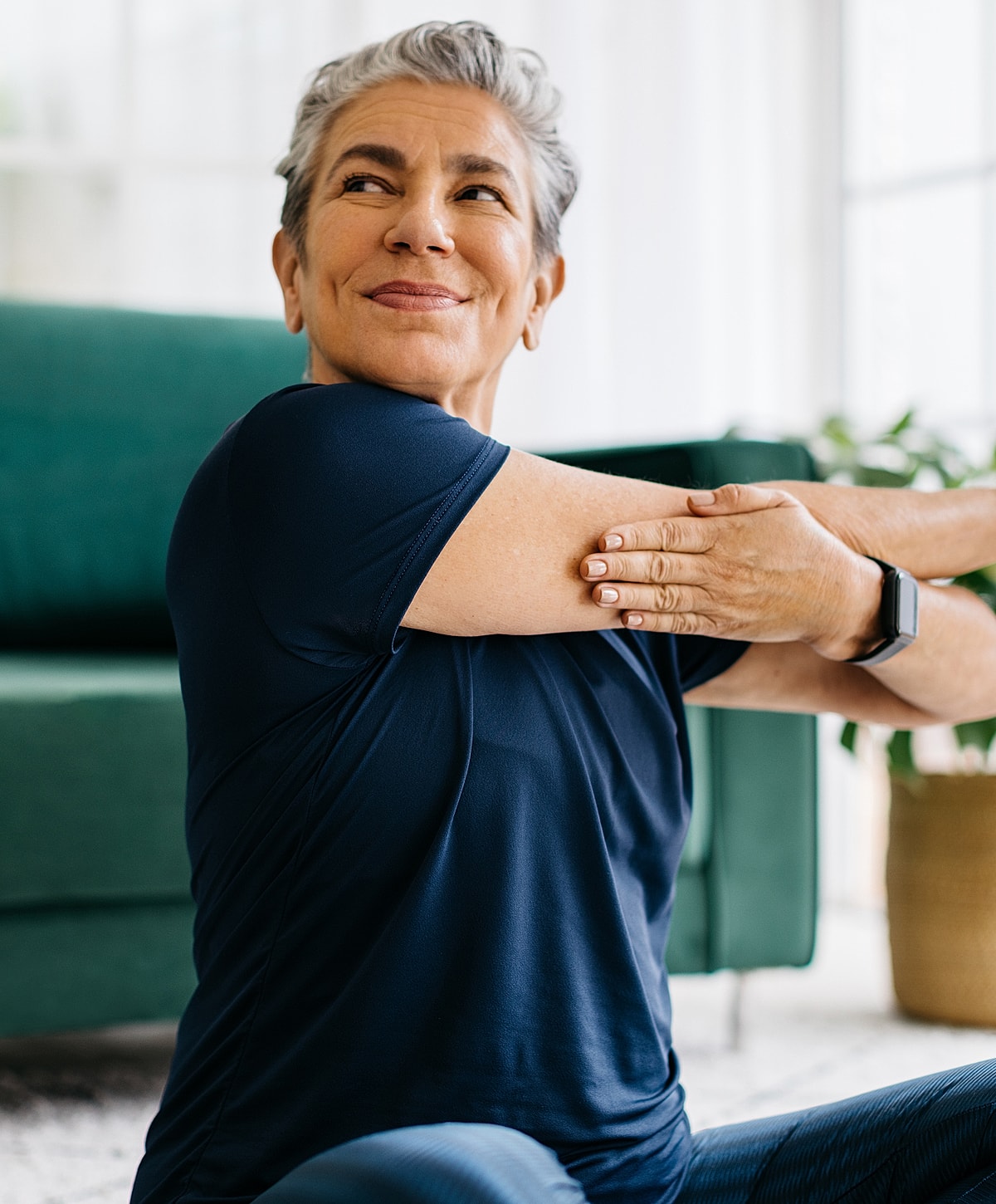 Older woman stretching in living room setting.