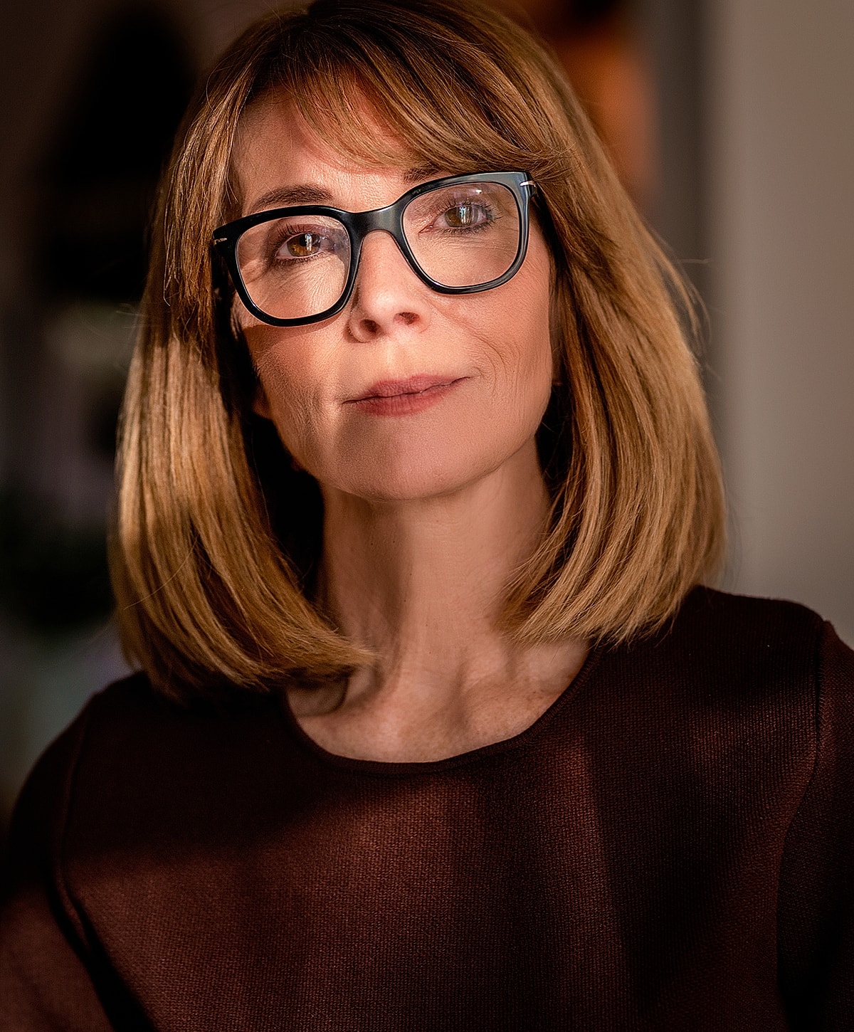 Woman with glasses and brown hair, soft lighting
