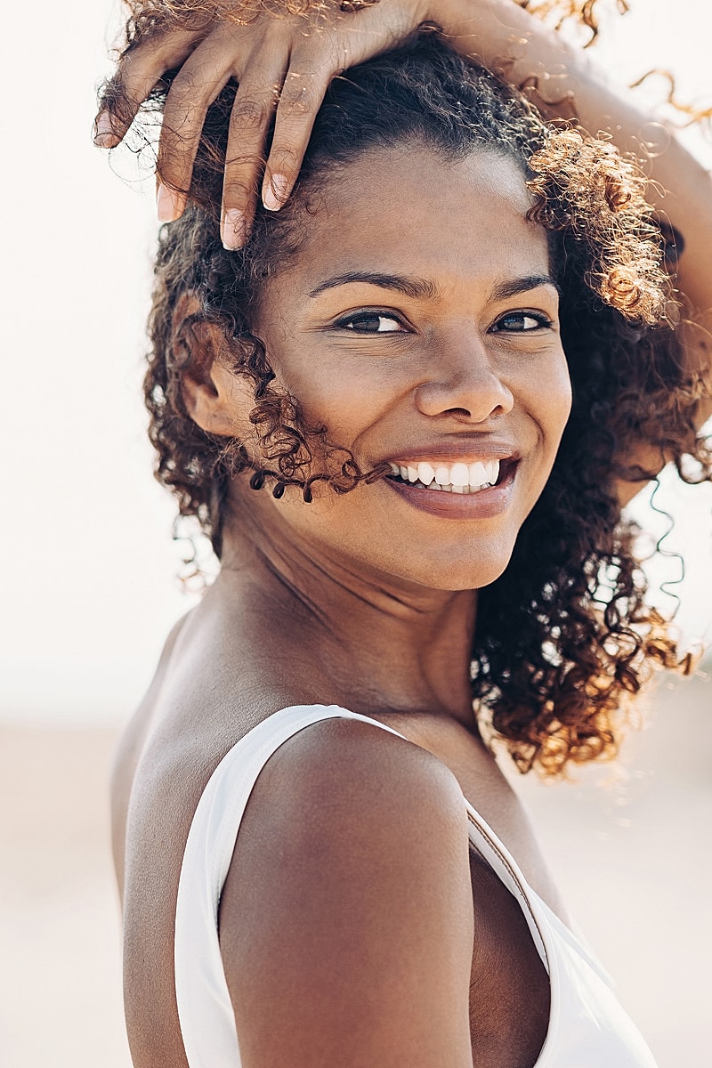 Smiling woman with curly hair outdoors.