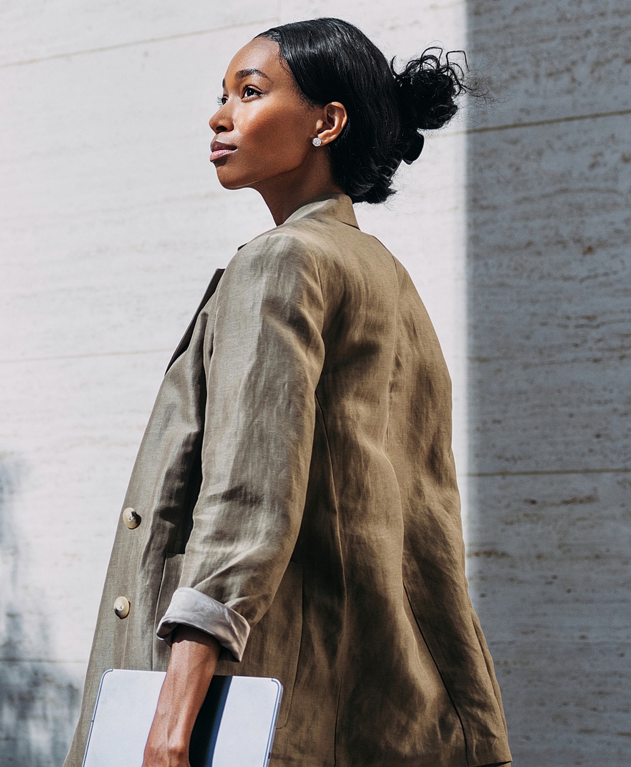 Woman in stylish blazer holding a tablet.