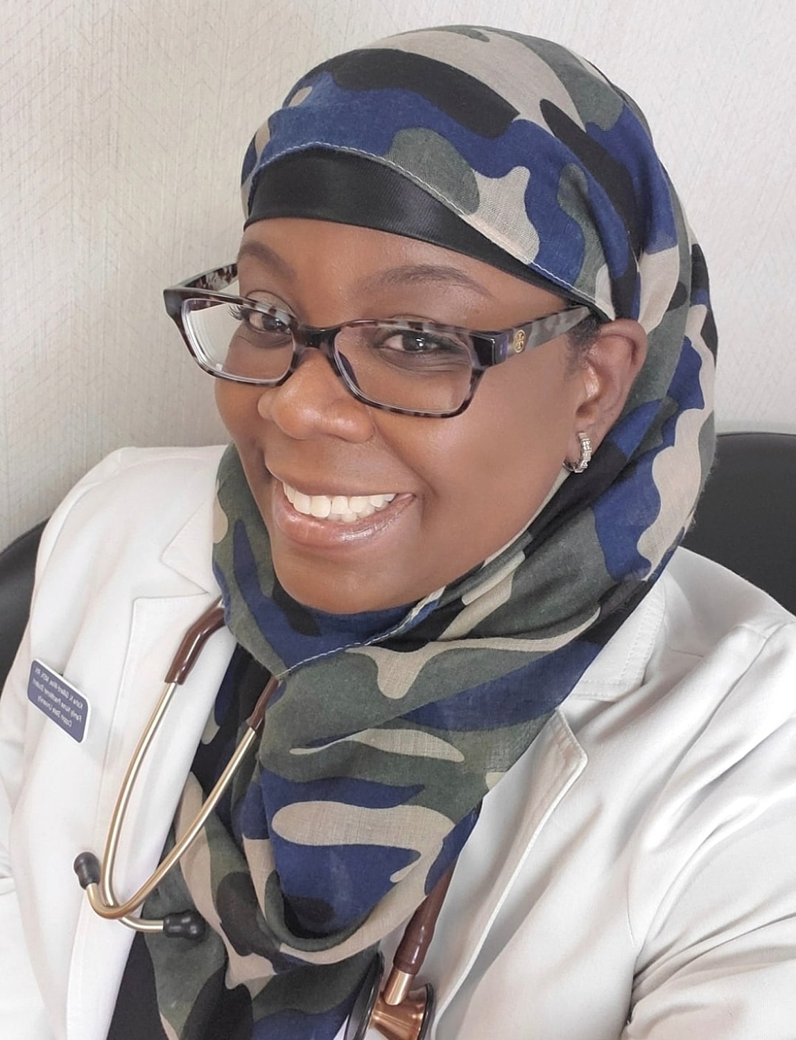 Smiling healthcare professional in camouflage hijab.