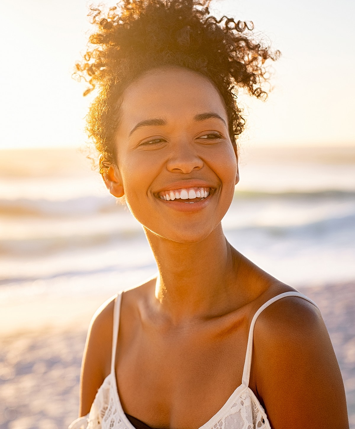 Smiling woman at beach during sunset.