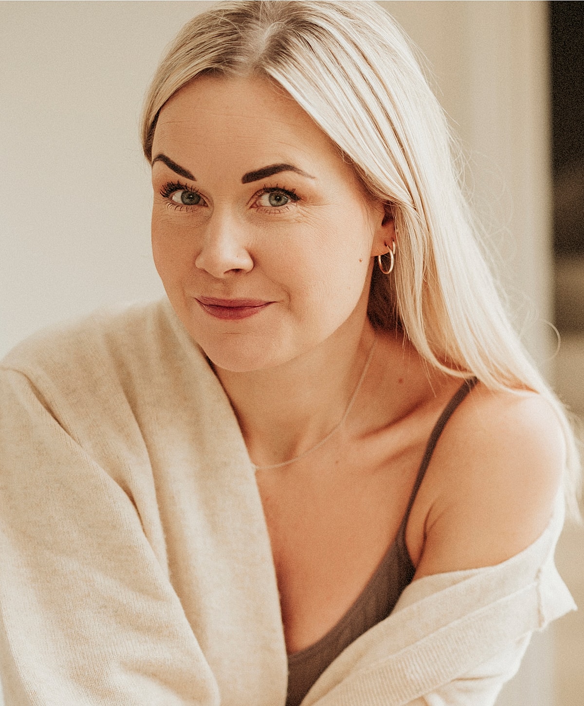 Woman with blonde hair smiling softly indoors.