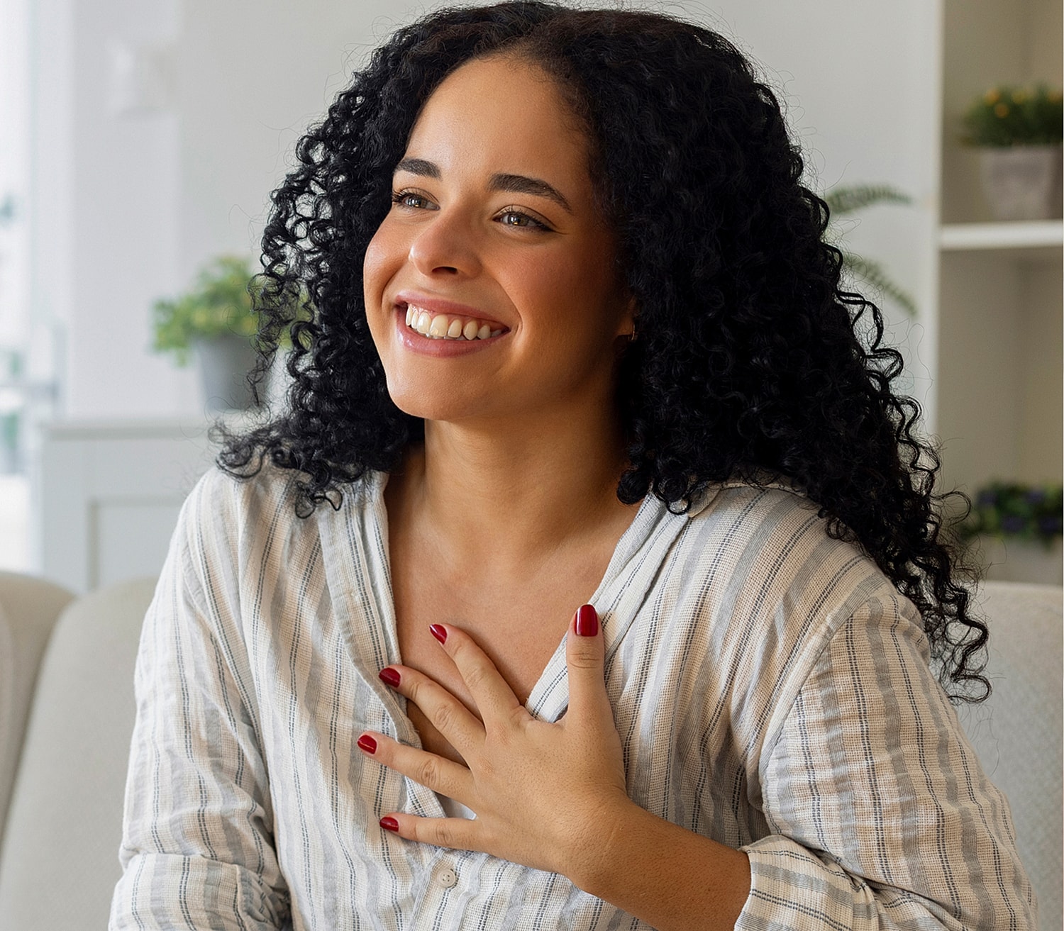 Smiling woman with curly hair in cozy setting.