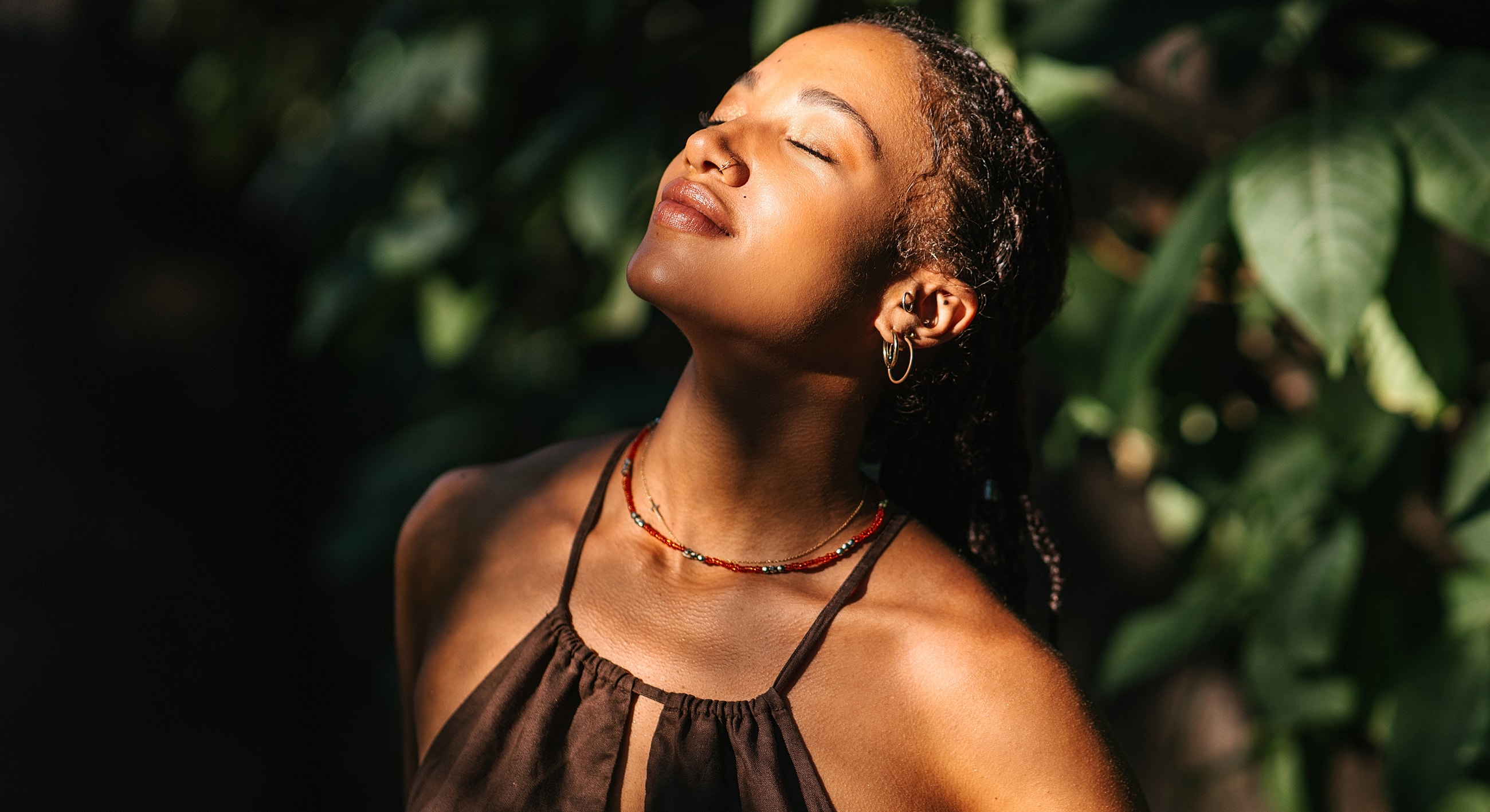 Woman enjoying sunlight in a lush setting.