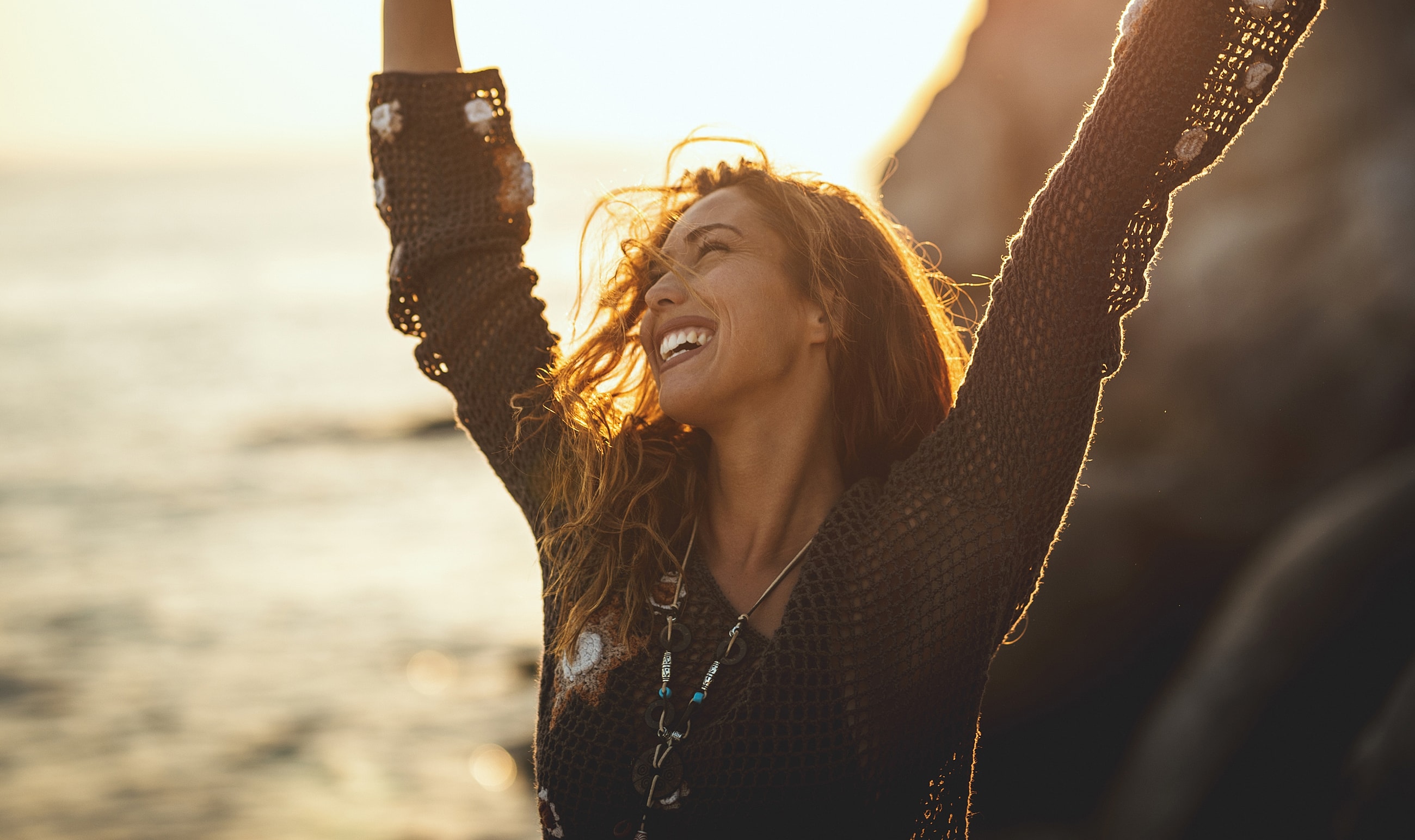 Happy woman enjoying a sunset by the beach.